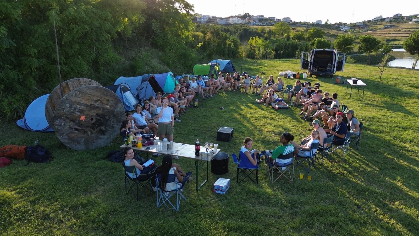 A youth group sitting in a circle between their tents at golden hour