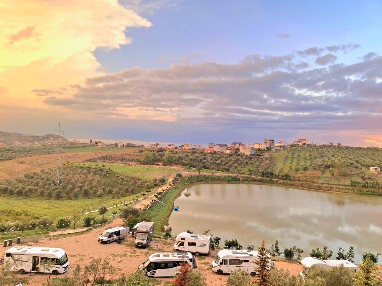 Campervans parked beside the lake at Wonderful Camping at sunset